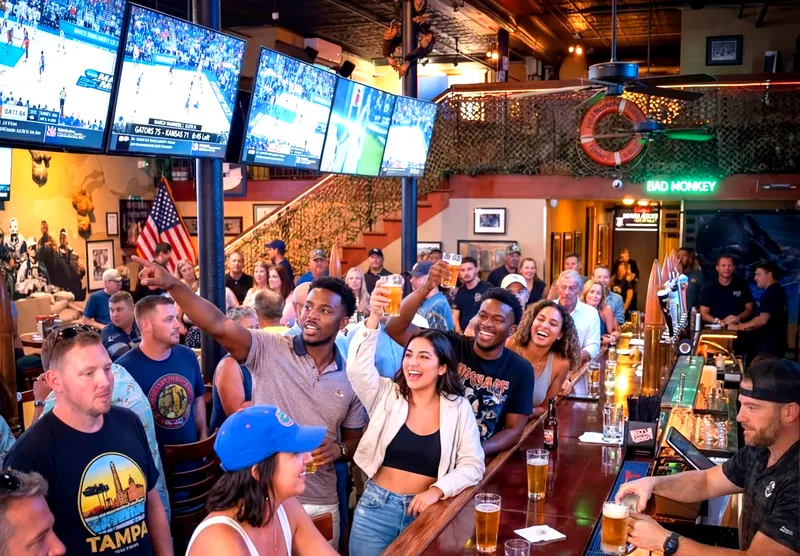 Fans cheering and raising beers at the bar during a college basketball game at Bad Monkey Ybor